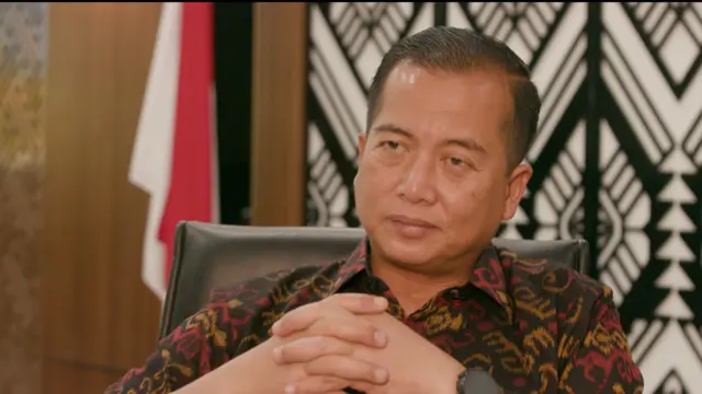 Foto Lalu Muhamad Iqbal mengenakan baju batik motif NTB, menautkan kedua tangannya di dada.