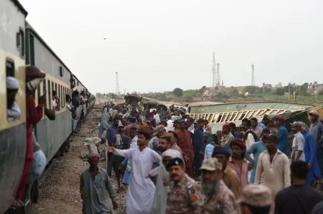 عمال السكك الحديدية يصلحون القضبان جنبا إلى جنب مع العربات المتضررة، بعد يوم من خروج قطار ركاب عن مساره في نواب شاه في 7 أغسطس/آب 2023