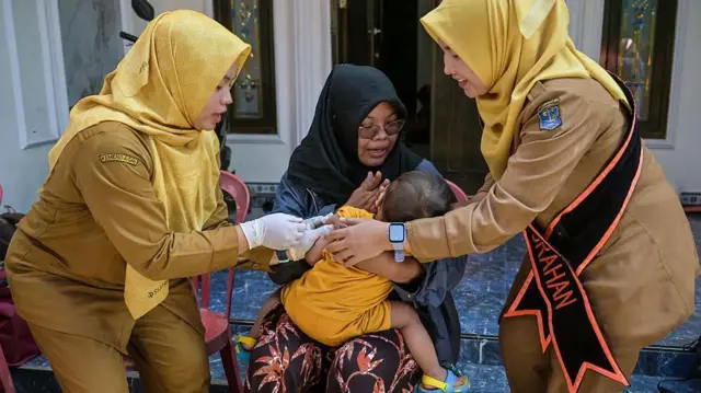 Seorang petugas kesehatan memberikan vaksin campak kepada seorang anak selama imunisasi simultan di Surabaya pada 15 September 2025