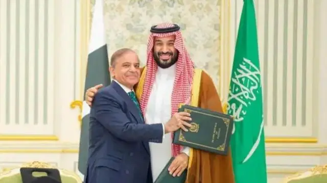 सऊदी अरब के क्राउन प्रिंस मोहम्मद बिन सलमान और पाकिस्तान के प्रधानमंत्री शहबाज़ शरीफ़ हाथों में फ़ाइलें लिए कैमरे के सामने गर्मजोशी भरी मुस्कान के साथ पोज़ दे रहे हैं. शहबाज़ शरीफ़ का एक हाथ बिन सलमान की बांह थामे हुए है और बिन सलमान का एक हाथ शरीफ़ के कंधे पर रखा हुआ है.