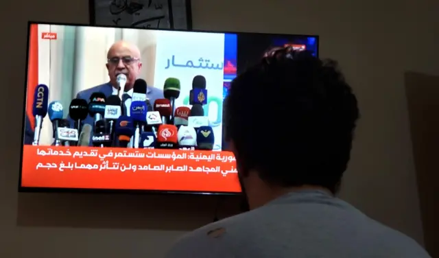 2025年8月30日，在也门萨那，一名男子正在观看胡塞武装总理艾哈迈德·拉哈维的电视画面。也门胡塞武装证实，艾哈迈德·拉哈维在8月28日以色列空袭首都时丧生。