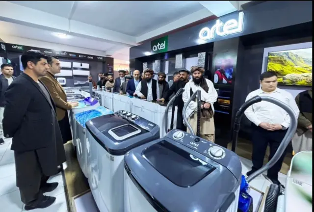 Afg'onistonlik tadbirkorlar Artel do'konida sotuvdagi maxsulatlarni ko'rishyapti