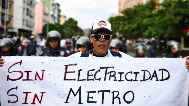 Manifestante protesta em Caracas com um cartaz dizendo 'Sem eletricidade, sem metrô'