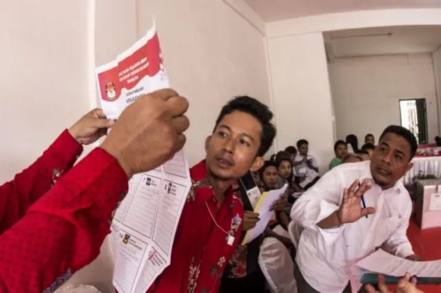 Petugas pemilu Indonesia memegang surat suara selama penghitungan suara setelah pemilihan legislatif Indonesia pada 9 April 2014 di Batam, Pulau Riau, Indonesia.