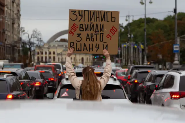 Một cô gái giơ tấm biển kêu gọi dừng lại và tưởng niệm những người đã ngã xuống trong cuộc chiến Nga–Ukraine, trong thời khắc cả nước mặc niệm trên phố Khreshchatyk ở Kyiv, Ukraine, ngày 24 tháng 9 năm 2025.