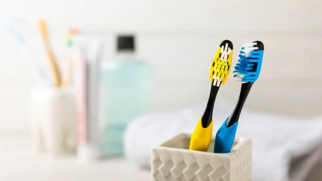 Blue and yellow toothbrushes shown in textured holder