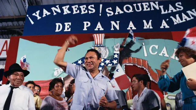 Manuel Antonio Noriega delante de una pancarta que dice "Yankees saquen las manos de Panamá"
