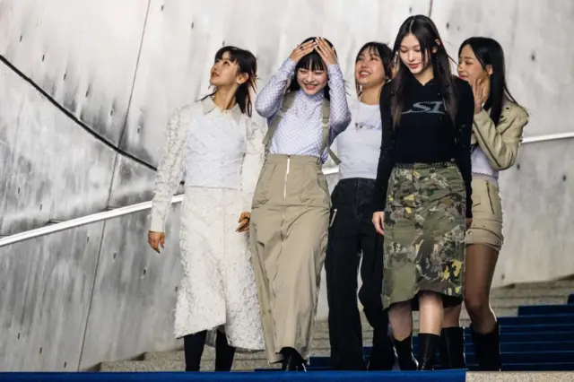 Anggota grup K-pop Korea Selatan NewJeans menyapa penggemar saat mereka berjalan di atas karpet biru di Seoul Fashion Week di Dongdaemun Design Plaza di Seoul pada 15 Maret 2023.