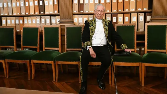 Mario Vargas Llosa sentado durante cerimônia em Paris
