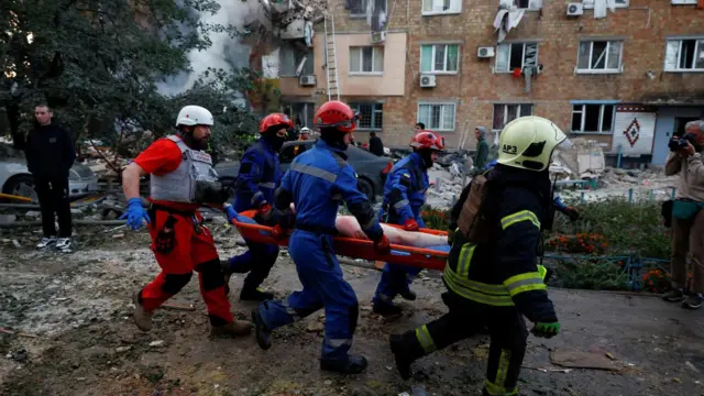 Ліквідація наслідків атаки на будинок, рятувальники несуть людину на ношах
