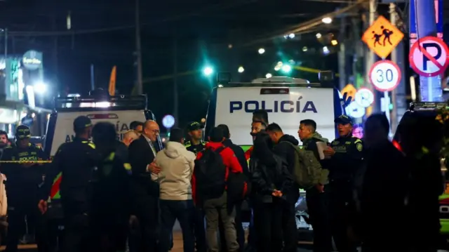 事件現場で目撃者らと話をする警察官や捜査官。奥には警察車両が停まっている