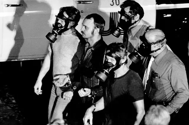 Jan-erik Ollson, gaz maskeli polislerce götürülürken.