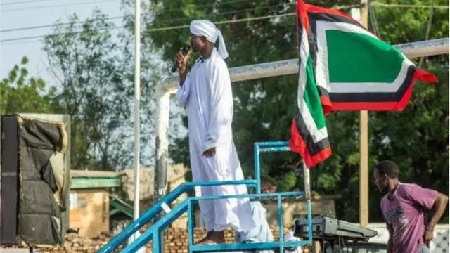 One imam dey perform im Eid sermon to crowds for Wad Madani - one city where many from di capital, Khartoum dey hide