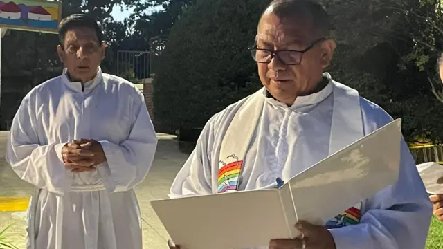 O padre Vidal Rivas (dir.), pároco da Igreja Episcopal de São Mateus em Hyattsville, Maryland, faz leitura durante o festival de São Francisco de Assis, ao lado de outro sacerdote.