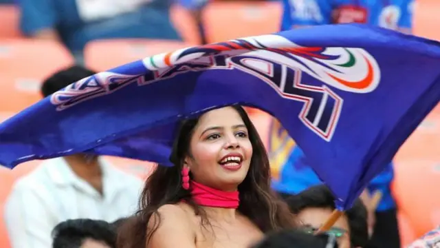 क्रिकेट मैच में झंडा लहराती एक प्रशंसक