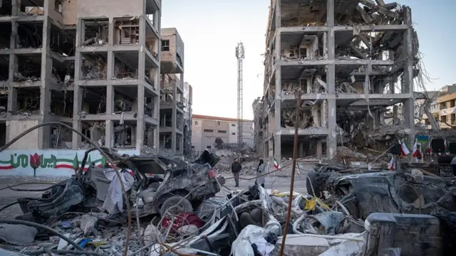 伊朗德黑兰某处居民视察美以联合空袭后的破坏情况，绘上了伊朗国旗图案的围墙附近断壁颓垣（9/3/2026）