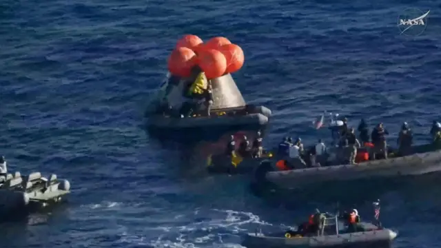 El personal de recuperación abre la escotilla lateral de la cápsula tripulada Artemis II que flota en el océano Pacífico tras el amerizaje