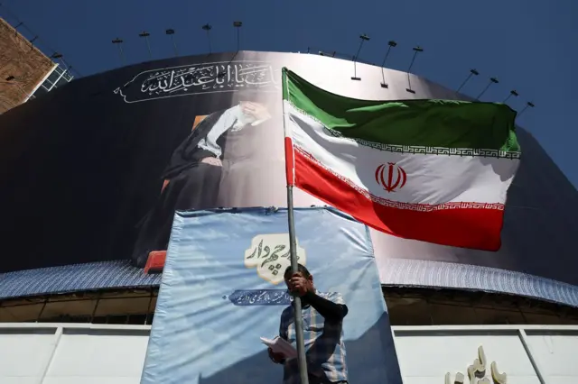 رجل يحمل العلم الإيراني في أحد شوارع طهران، إيران، في 15 يونيو/حزيران 2026، بعد أن أعلن مسؤولون أمريكيون وإيرانيون عن توصلهم إلى اتفاق لإنهاء الحرب وإعادة فتح مضيق هرمز.