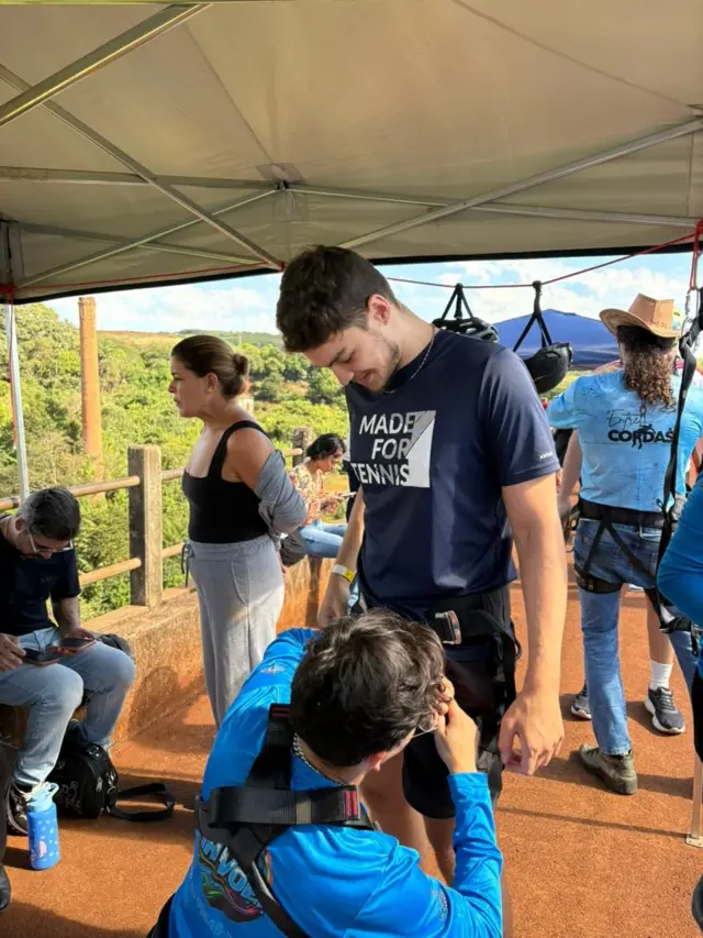 Imagem de um homem ajustando os equipamentos antes do salto. 