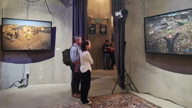 Двоје људи посматрају фотографије на изложби