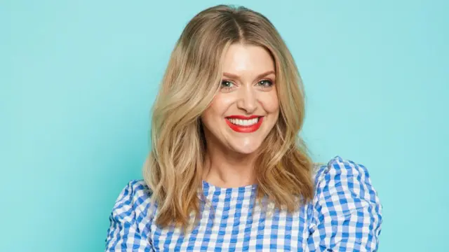 Foto de Anna Williamson, uma mulher loira e sorridente num vestido azul e branco quadriculado