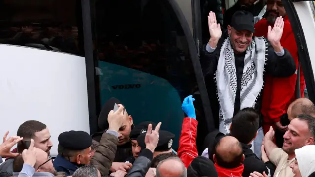 أسير فلسطيني سابق أفرجت عنه إسرائيل يحظى بالهتاف من حشد من الناس وهو يخرج من حافلة في مدينة رام الله بالضفة الغربية المحتلة في 8 فبراير 2025، كجزء من عملية التبادل الخامسة بموجب هدنة هشة في غزة.