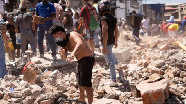 Pessoas sobre os escombros buscam sobreviventes em Cali.