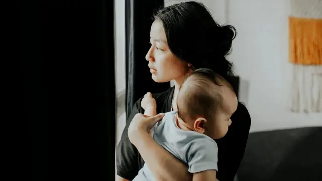 Foto ilustrasi pengasuh anak yang sedang menggendong balita.