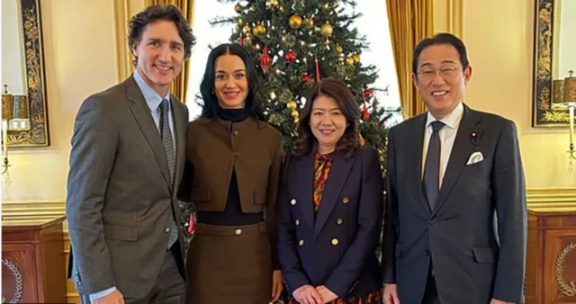 Katy Perry ve Trudeau solda, Eski Japonya Başbakanı Fumio Kishida ve eşi sağda duruyor. Arkada bir noel ağacı var.