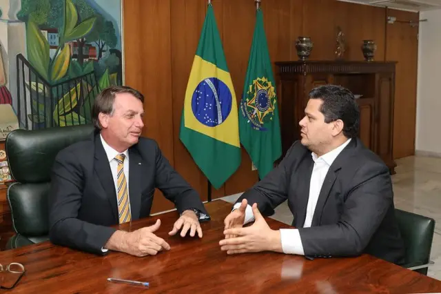 Bolsonaro e Alcolumbre sentados em uma mesa, conversando