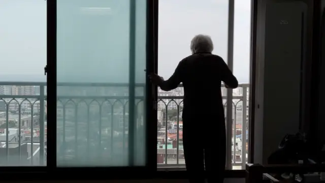 할머니가 창 밖을 바라보고 있다