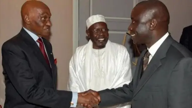 Le président Aboudoulaye Wade (à gauche) en costume noir et cravate rouge et son Premier ministre Idrissa Seck (à droite) qui lui sourit.