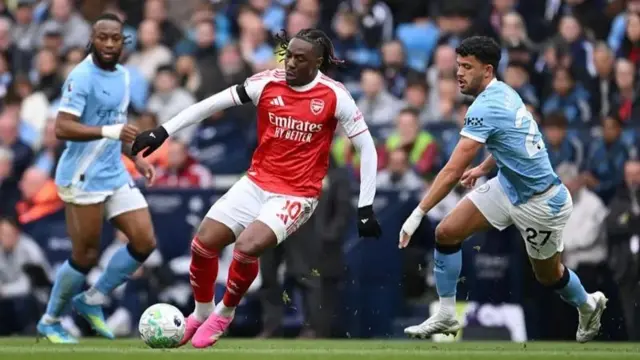 Eberechi Eze of Arsenal dey for di middle of two Manchester City players