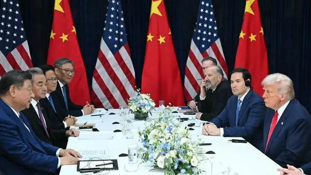 スーツ姿の米中の代表団がテーブルを挟んで向き合っている。奥には両国の国旗が交互に立てられている