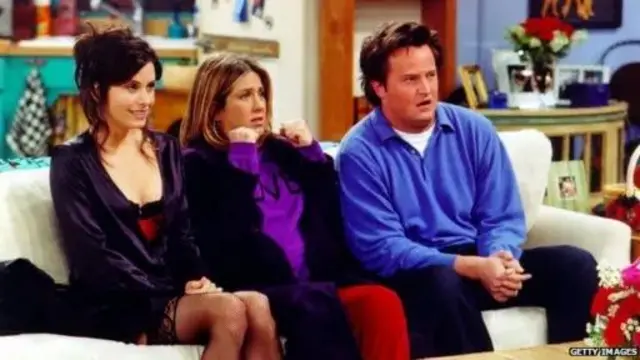 Monica, Rachel e Chandler sentados no sofá