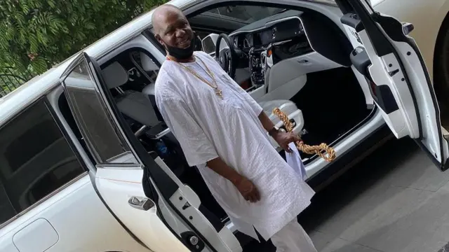 Foto Chief Ezokafor yi uwe ọcha ma nọrọ n'ihu ụgbọala ya