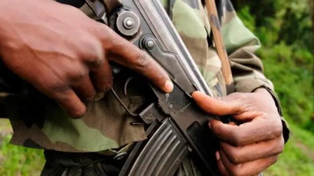 Un soldat en uniform, les mains posées sur son arme.