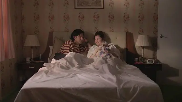 Кадр із серіала "Занадто". Молоді чоловік і жінка сидять на ліжку у спальні і дивляться одне на одного