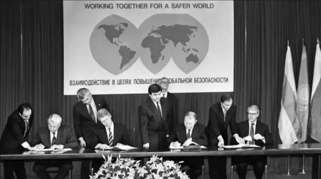 Чорно-біле фото підписання Будапештського меморандуму - на ньому російський президент Борис Єльцин, президент США Білл Клінтон, український лідер Леонід Кучма та британський прем'єр Джон Мейджор сидять за столом і підписують документи, біля них стоять радники