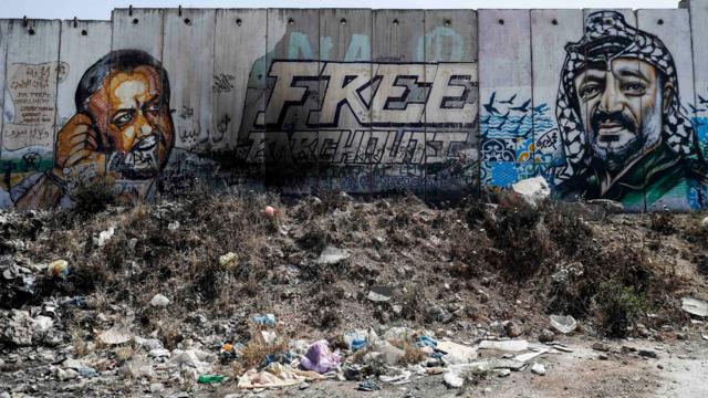 A picture taken on 27 May 2017 between Jerusalem and the West Bank city of Ramallah shows a mural of Fatah leader Marwan Barghuti (L) and late Palestinian leader Yasser Arafat on a section of Israel's controversial separation wall.