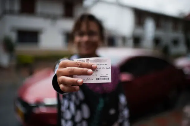 Mujer muestra su certificado electoral.