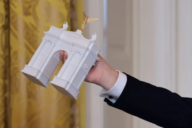 Президент США Дональд Трамп тримає модель Тріумфальної арки зі статуєю Леді Свободи на вершині під час бальної вечері у Східній кімнаті Білого дому у Вашингтоні, жовтень 2025