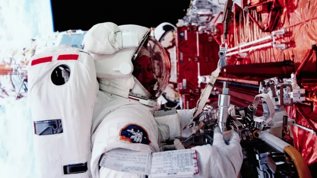Astronaut Kathryn C. Thornton on a extra-vehicular space walk, working to repair the Hubble Space Telescope during the eleven-day STS-61 mission. The Earth is visible behind her. December 8, 1993. | Location: above Earth. (