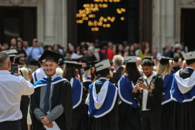 University students in their graduation gown in central London, posing for photos. 