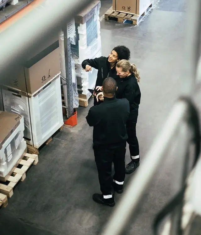 3 personnes debout dans un hangar.