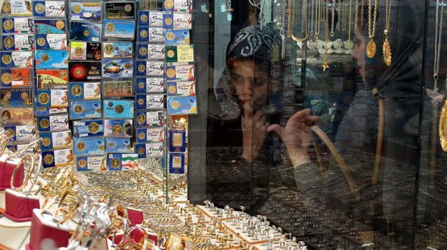 زنان ایرانی در ویترین یک جواهرفروشی در مرکز تهران به انگشترها و دستبندها نگاه می کنند، در حالی که قیمت طلا بالا رفته و سرمایه گذاران در بحبوحه نگرانی از وضعیت شکننده دلار به دنبال جایگزین هایی برای دلار بودند.