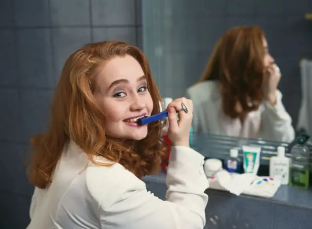 Penyanyi pop Inggris sedang menggosok gigi di rumah.