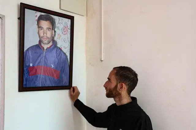 Nazakat looks at a portrait of his brother Adil Shah, who was killed during an incident in Pahalgam last year, at his new home in Hapatnar, Pahalgam, Jammu and Kashmir, India, on April 21, 2026. (Photo by Nasir Kachroo/NurPhoto via Getty Images)