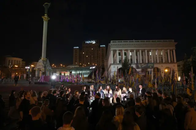 Колеги Вікторії Рощиної тримають її фотографії під час заходу на честь її пам'яті біля імпровізованого меморіалу загиблим українським воїнам на Майдані Незалежності в Києві, 11 жовтня 2025