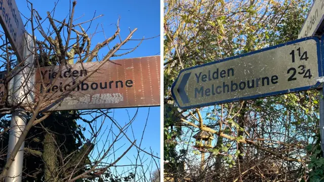 Dos señales de carretera sucias, cubiertas de zarzas y rodeadas de vegetación, indican la distancia a dos pueblos.
